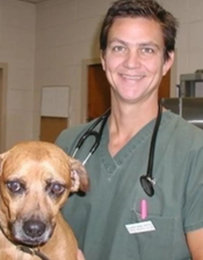 Dr. Steve Hendrix smiling at the camera while holding a dog
